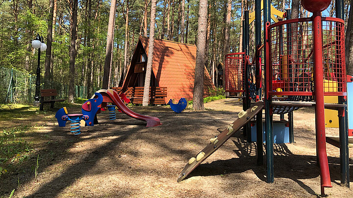Dziecięcy plac zabaw usytuowany w lesie.